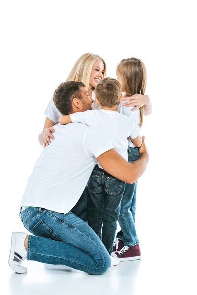 Glückliche Eltern lächeln, während sie niedliche Kinder in Weiß umarmen — Stockfoto