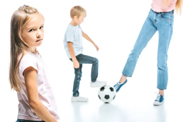 Вибірковий фокус сумної дитини, дивлячись на камеру біля дитини, грає в футбол з матір'ю ізольовано на білому — стокове фото