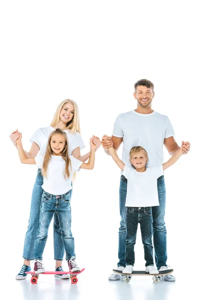 Glückliche Eltern halten Händchen von Sohn und Tochter auf weißen Penny-Brettern — Stockfoto
