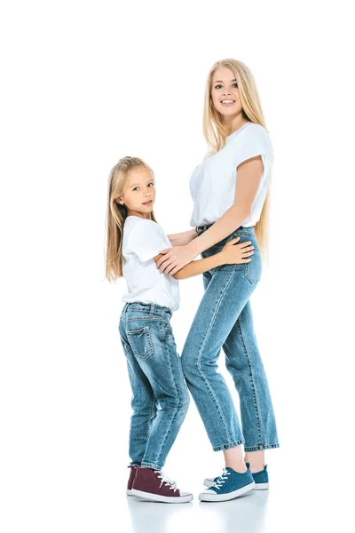 Bela mãe de pé e abraçando a filha no branco — Fotografia de Stock