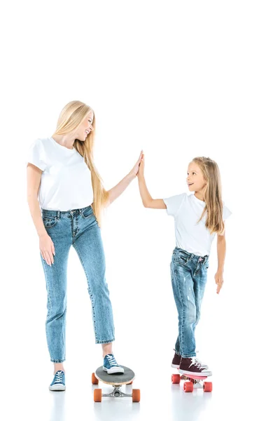 Happy mother giving high five to daughter riding penny board on white — Stock Photo