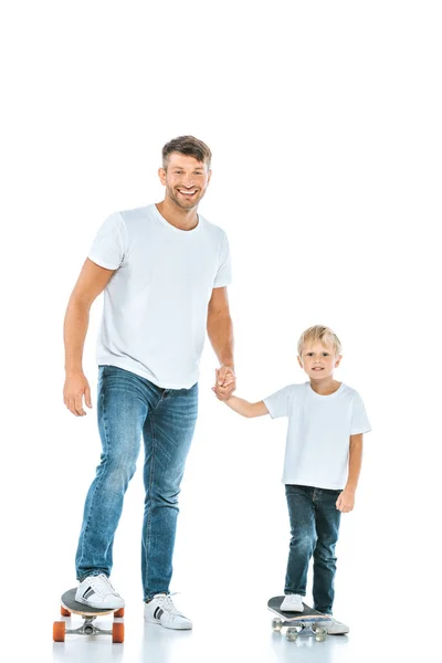 Felice padre tenendosi per mano con figlio e cavalcando penny tavole su bianco — Stock Photo