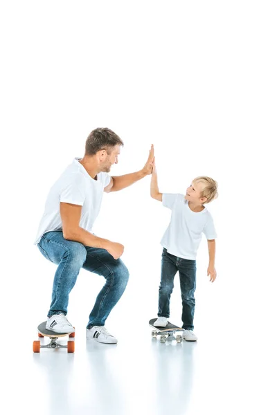 Glücklicher Vater gibt High Five an fröhlichen Sohn, der Penny Board auf Weiß reitet — Stockfoto
