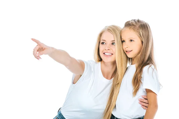 Happy woman pointing with finger while hugging daughter isolated on white — Stock Photo