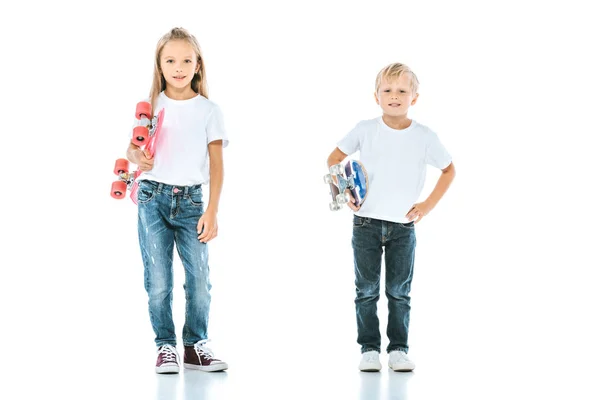 Happy kids smiling while holding penny boards on white — Stock Photo