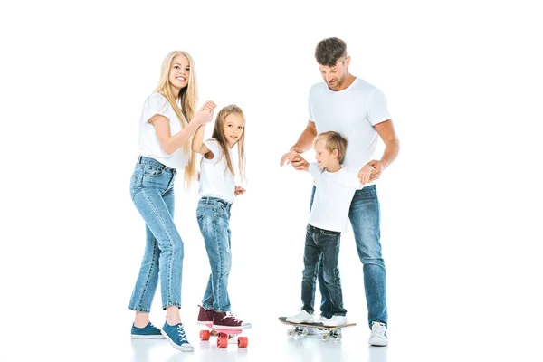 Glückliche Eltern halten Händchen von Kindern, die auf weißen Penny-Brettern reiten — Stockfoto