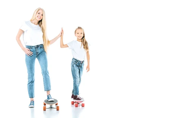 Feliz madre y niño dando alta cinco mientras que monta penny boards en blanco - foto de stock