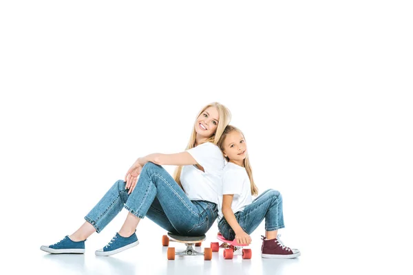 Alegre madre y niño sentado en penny boards en blanco - foto de stock