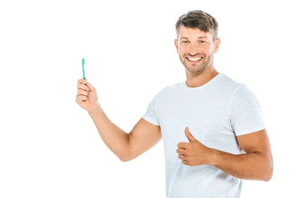 Uomo allegro tenendo spazzolino da denti mentre mostra pollice su isolato su bianco — Foto stock