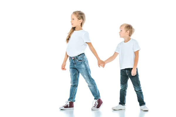 Two cute kids holding hands and walking on white — Stock Photo