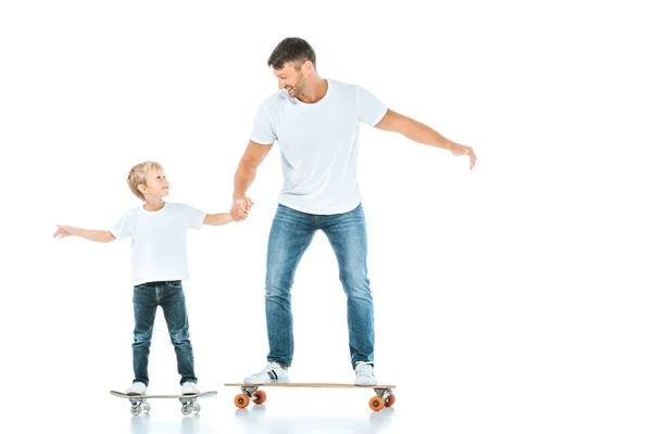 Felice padre e figlio che si tiene per mano mentre cavalca penny tavole su bianco — Stock Photo