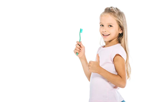 Bambino felice tenendo spazzolino da denti e mostrando pollice su isolato su bianco — Foto stock