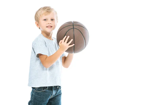 Menino bonito segurando basquete e sorrindo isolado no branco — Fotografia de Stock