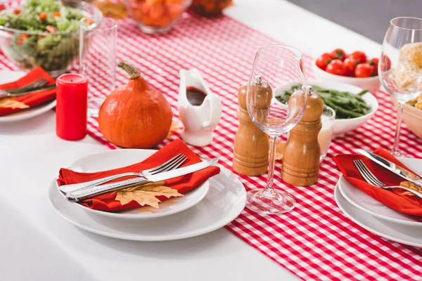 Table with plates, glasses, candle, cutlery, pepper mill, salt mill and pumpkin in Thanksgiving day — Stock Photo