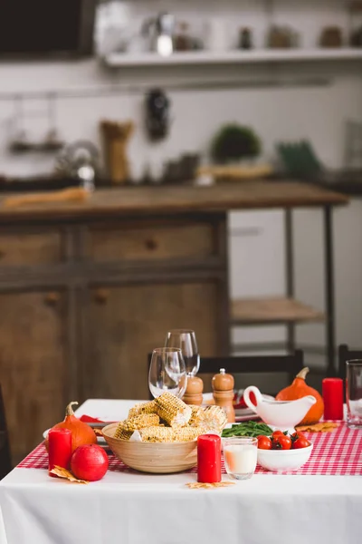Стол с помидорами черри, стаканами, свечами, перечной мельницей, соляной мельницей, кукурузой и тыквами в День Благодарения — стоковое фото