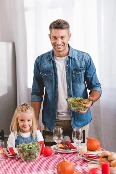 Father holding salad and cute daughter smiling and looking at camera in Thanksgiving day — Stock Photo