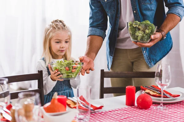 Cropped view of father giving bowl with salad to cute daughter in Thanksgiving day — Stock Photo