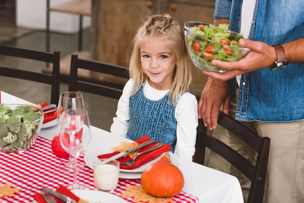 Vue recadrée du père tenant bol avec salade et fille mignonne souriant et regardant la caméra dans le jour de Thanksgiving — Photo de stock