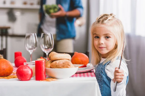 Messa a fuoco selettiva della figlia carina che tiene coltello e sorride nel giorno del Ringraziamento — Foto stock