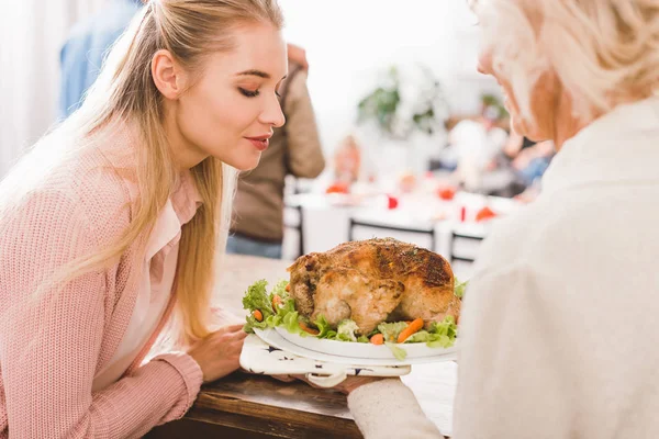 Madre e hija sosteniendo el plato con sabroso pavo en el día de Acción de Gracias - foto de stock