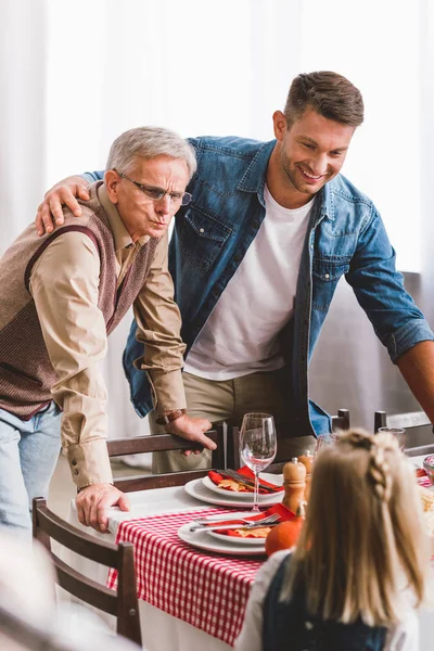 Selective focus of smiling father and grandparent looking at kid in Thanksgiving day — Stock Photo