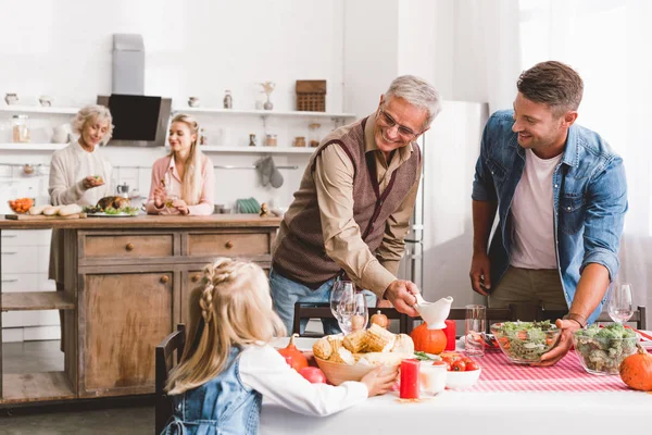 Selektiver Fokus lächelnder Vater und Großeltern auf Kind und gedecktem Tisch zum Erntedank — Stockfoto