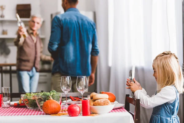 Selective focus of cute kid smiling and holding cutlery in Thanksgiving day — Stock Photo