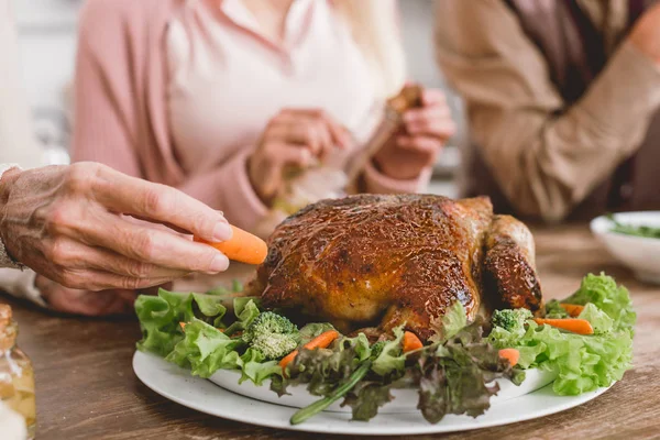 Vista ritagliata di donna che mette la carota a piatto con tacchino saporito in giorno del Ringraziamento — Foto stock