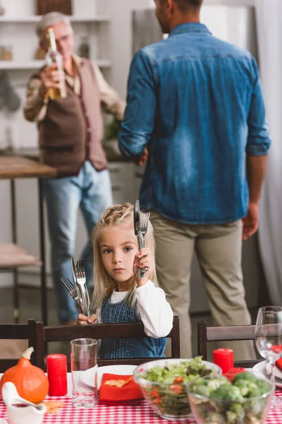 Selective focus of cute kid smiling and holding cutlery in Thanksgiving day — Stock Photo