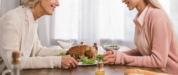 Panoramic shot of smiling mother and daughter holding plate with turkey in Thanksgiving day — Stock Photo
