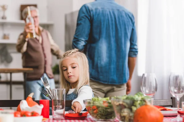 Selective focus of cute kid smiling and putting on table cutlery in Thanksgiving day — Stock Photo