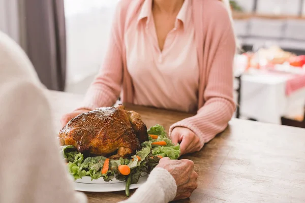 Cropped view of mother and daughter holding plate with turkey in Thanksgiving day — Stock Photo