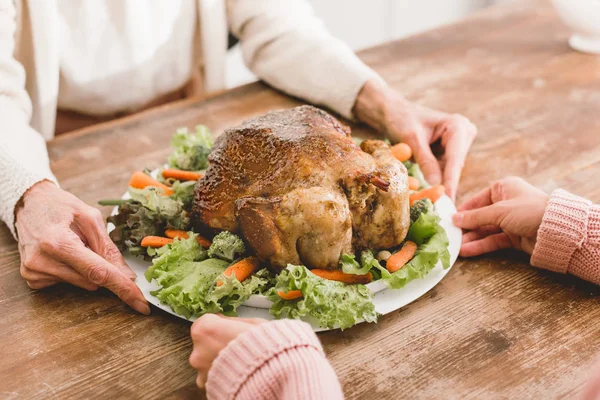 Vue recadrée de la mère et de la fille tenant la plaque avec la dinde le jour de Thanksgiving — Photo de stock