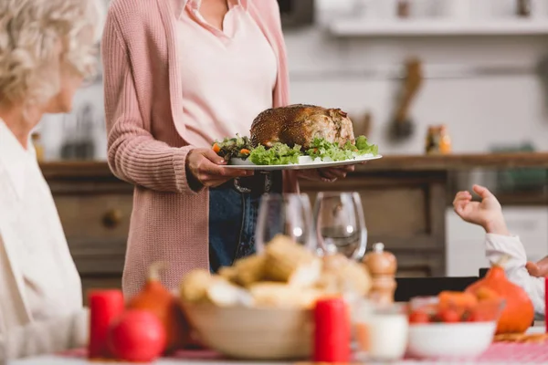 Cropped view of mother holding plate with turkey in Thanksgiving day — Stock Photo