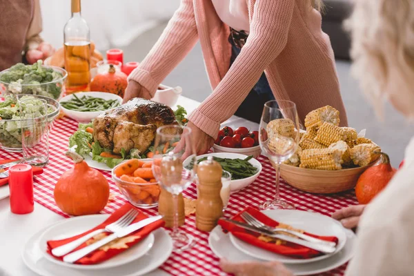 Cropped view of mother putting on table plate with turkey in Thanksgiving day — Stock Photo