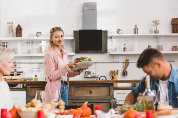 Selective focus of smiling mother holding plate with tasty turkey in Thanksgiving day — Stock Photo