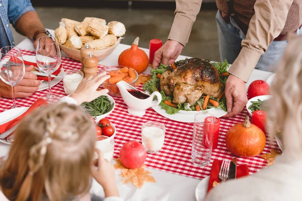 Обрезанный вид дедушки положить на стол тарелку с индейкой в День Благодарения — стоковое фото
