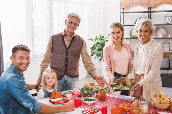 Membres de la famille assis à table et tenant assiette avec dinde le jour de Thanksgiving — Photo de stock