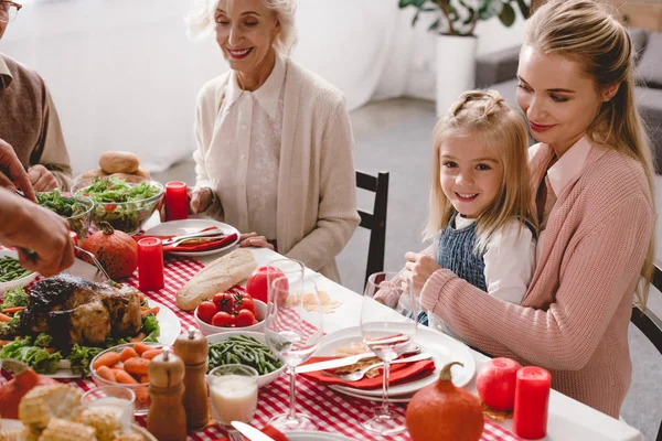 Vue recadrée des membres de la famille assis à table et le père couper dinde savoureuse le jour de Thanksgiving — Photo de stock