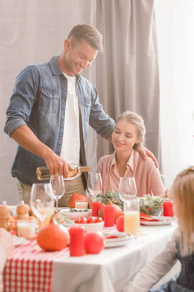 Family members sitting at table and smiling father pouring wine in Thanksgiving day — Stock Photo