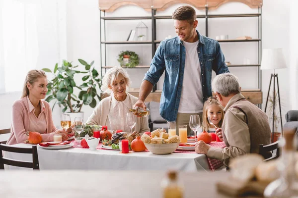 Family members sitting at table and smiling father pouring wine in Thanksgiving day — Stock Photo