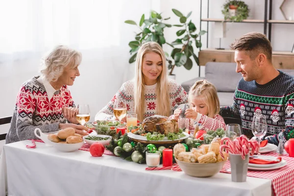 Lächelnde Familienmitglieder sitzen am Tisch und feiern Weihnachten — Stockfoto