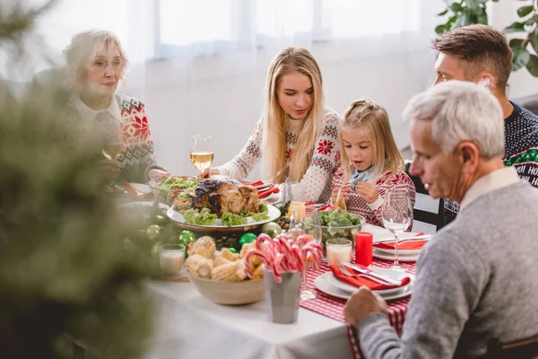 Focus selettivo dei membri della famiglia seduti a tavola e che celebrano il Natale — Foto stock