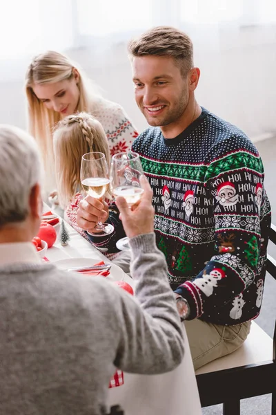 Selektiver Fokus von Familienmitgliedern, die an einem Tisch sitzen und in der Weihnachtszeit mit Weingläsern klirren — Stockfoto