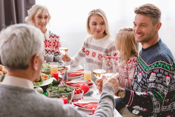 Membri della famiglia seduti a tavola e clinking con bicchieri di vino a Natale — Foto stock