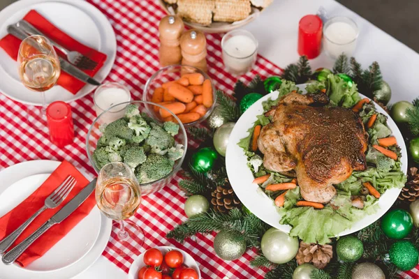 Vista de ángulo alto de verduras, pavo, tomates cherry, copa de vino, velas en la mesa en Navidad - foto de stock