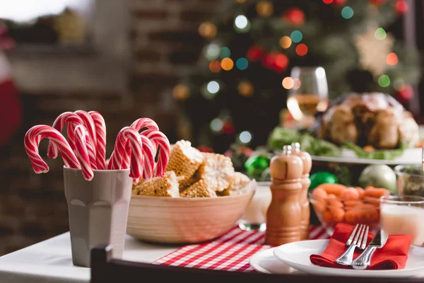 Focus selettivo di bastoncini di zucchero, mais, piatti e posate in tavola a Natale — Foto stock