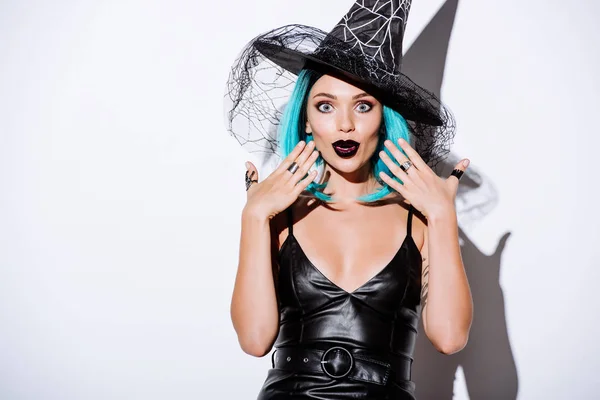 Impactado chica en traje de Halloween bruja negro con pelo azul sobre fondo blanco - foto de stock