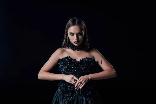 Asustadiza chica vampiro en vestido gótico negro aislado en negro - foto de stock