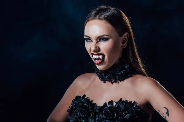 Assustador vampiro menina com presas em preto vestido gótico isolado no preto — Fotografia de Stock